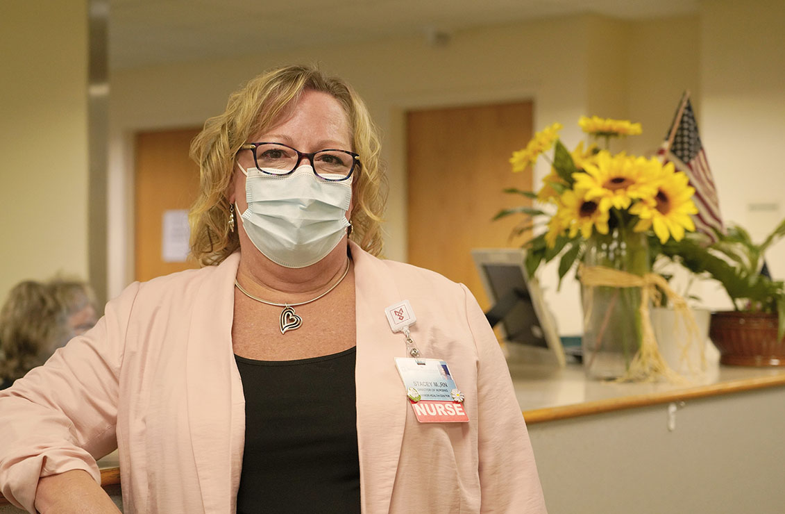 Woman wearing a mask standing in front of a nurses' station
