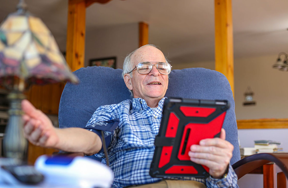 Elderly man uses iPad to speak to a nurse