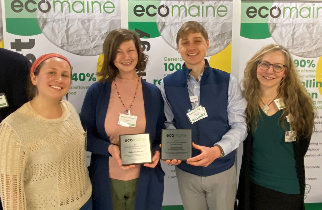 four women standing together holding awards in front of Ecomaine backdrop